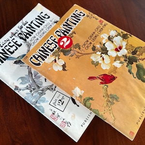May include: Two vintage books on Chinese painting. One book has a white cover with a bird illustration and the text "Easy ways to do Chinese Painting". The other book has an orange cover with a bird and floral illustration.