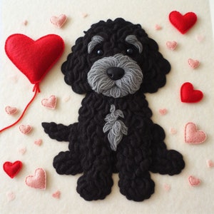 May include: A black felt dog with grey fur accents, standing on a white background with red and pink felt hearts scattered around it. A red felt heart with a string attached is in the top left corner.