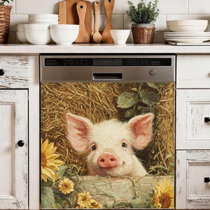 May include: A dishwasher cover featuring a close-up of a piglet peeking out from behind a wooden fence. The piglet has pink ears and a pink snout, with a backdrop of hay and sunflowers. The cover adds a touch of rustic charm to the kitchen.