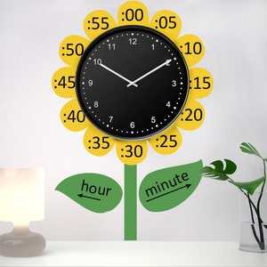 May include: A black clock with white hands is displayed on a white wall. The clock is surrounded by yellow petals with numbers representing minutes. The petals are attached to a green stem with green leaves. The words "hour" and "minute" are written on the leaves with arrows pointing to the clock.