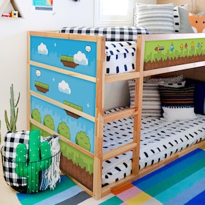 Könnte beinhalten: Ein hölzernes Etagenbett mit Paneelen im Pixel-Videospiel-Design. Die blauen Paneele zeigen schwebende Inseln und Wolken. Das Bett hat eine schwarz-weiß gemusterte Bettdecke und einen bunten Teppich.