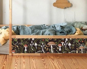 May include: A wooden bed frame with a light blue and yellow bedding set. The bed has a decorative border with a mushroom and floral pattern. The bed is in a room with a wooden floor and white walls.