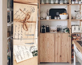 May include: A vintage-style refrigerator with a decorative design featuring old letters and stamps. The refrigerator is in a kitchen with wooden shelves and cabinets.