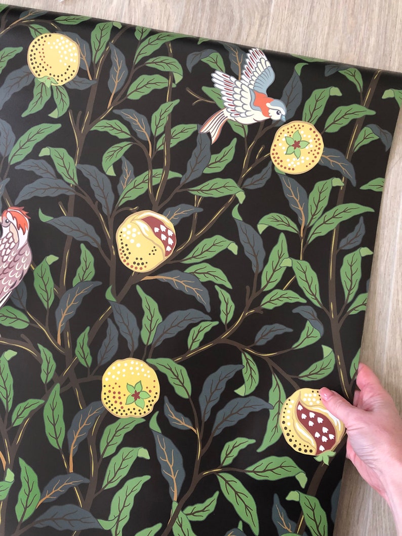 May include: Black wallpaper with a repeating pattern of green leaves, yellow pomegranates, and white birds. The birds are flying and perched on the branches of the trees.