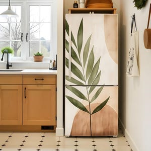 Puede incluir: Un refrigerador blanco con una cubierta de puerta extra&iacute;ble que presenta un dise&ntilde;o de hoja de palma verde y formas abstractas en tonos marrones y beige.