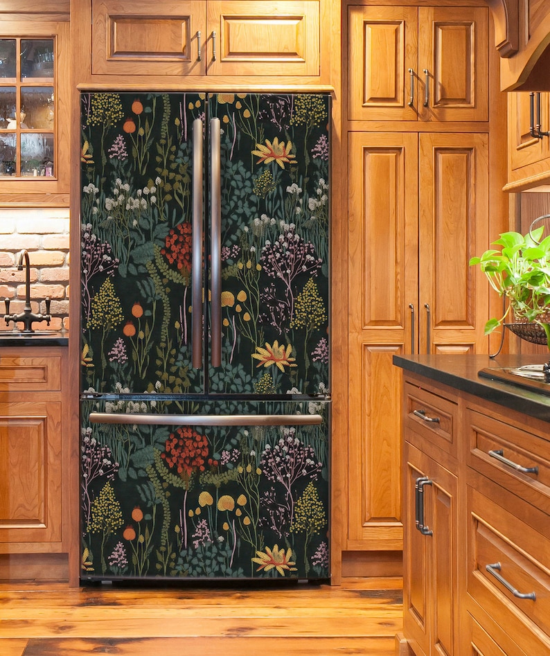 May include: A stainless steel refrigerator with a black floral patterned design. The refrigerator is in a kitchen with wood cabinets.