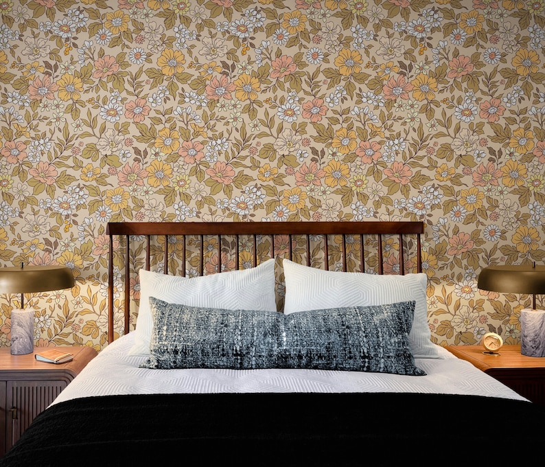 May include: A bed with a wooden headboard and a white duvet cover. The bed has two white pillows and a blue patterned throw pillow. The headboard is against a wall with a floral wallpaper featuring a pattern of yellow, orange, and white flowers.