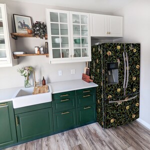 May include: A green kitchen with white cabinets, a stainless steel refrigerator with a floral design, and a white countertop. The refrigerator has a water dispenser and an ice maker.