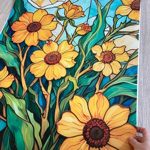 May include: A stained glass style print featuring yellow flowers with brown centers and green leaves on a blue background.