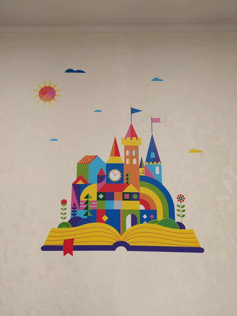 May include: A colorful illustration of a castle emerging from an open book. The castle is made of geometric shapes and has a rainbow archway. The book is yellow with blue pages and a red bookmark.