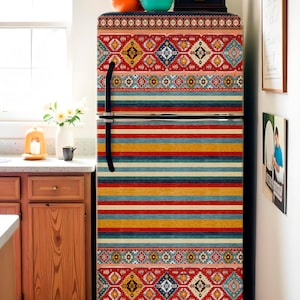 May include: A refrigerator with a colorful, patterned wrap. The wrap features a mix of horizontal stripes and geometric designs in red, blue, yellow, and other colors. A black clock and bowls sit on top.