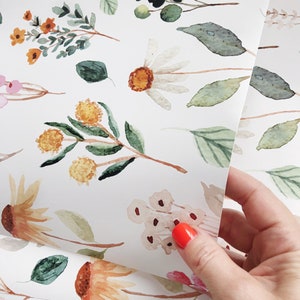 May include: White wrapping paper with a repeating pattern of watercolor flowers and leaves in shades of green, yellow, orange, pink, and brown.