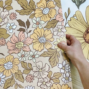 May include: A roll of beige wallpaper with a floral pattern featuring yellow, pink, and white flowers with brown leaves.