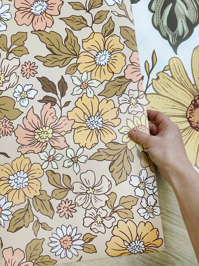 May include: A roll of beige wallpaper with a floral pattern featuring yellow, pink, and white flowers with brown leaves.