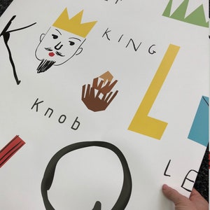 May include: A white background with black, yellow, brown, red, and green illustrations of letters, words, and simple drawings. The words "Flower", "King", "Knob", and "Lemon" are visible.