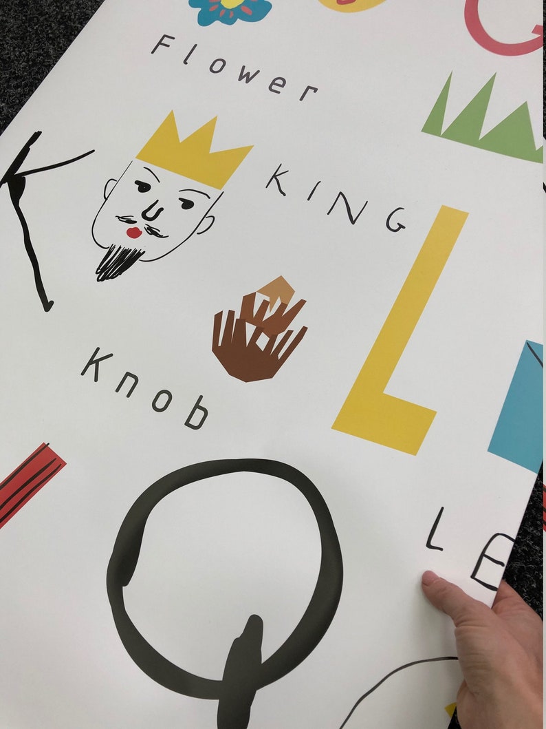 May include: A white background with black, yellow, brown, red, and green illustrations of letters, words, and simple drawings. The words "Flower", "King", "Knob", and "Lemon" are visible.