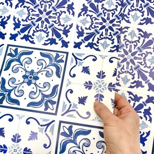 May include: Blue and white patterned tile stickers. The stickers are arranged in a grid pattern and are being peeled off of a sheet.