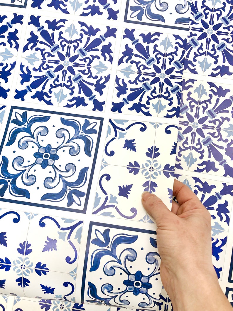 May include: Blue and white patterned tile stickers. The stickers are arranged in a grid pattern and are being peeled off of a sheet.