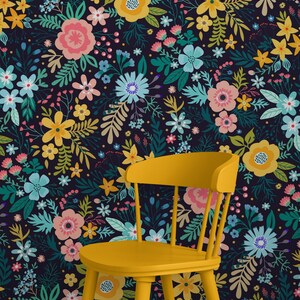 May include: A yellow wooden chair stands in front of a floral wallpaper. The wallpaper features a dark background with a pattern of colorful flowers in shades of pink, yellow, blue, and green. The chair has a curved back and four legs.