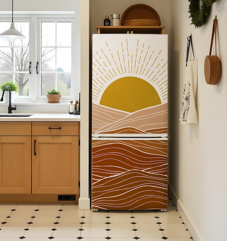 K&ouml;nnte beinhalten: Ein K&uuml;hlschrank mit einem individuellen Design mit einer gelben Sonne und einem geschichteten braunen und beigen Berg- und Wellenmuster. Das Design bedeckt die gesamte Vorderseite des K&uuml;hlschranks.