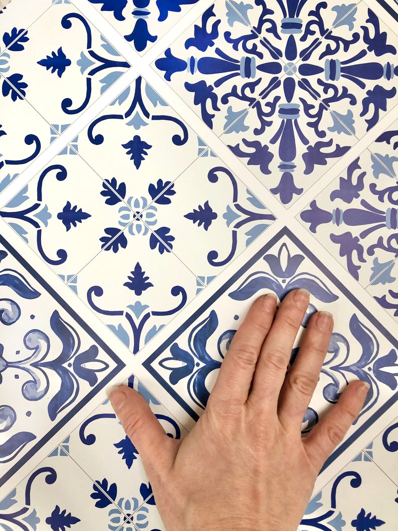 May include: Blue and white patterned tile stickers with a hand placed on top of them. The tiles have a traditional design with floral motifs.