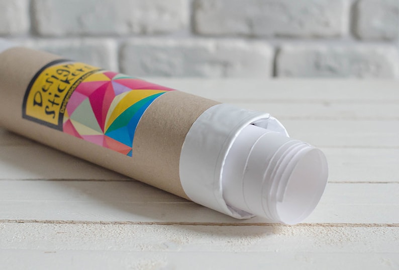 Puede incluir: Un p&oacute;ster enrollado en un tubo de cart&oacute;n blanco. El tubo tiene una pegatina colorida con el texto "Design Stickers".