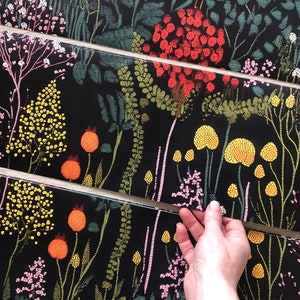 May include: A black background with a repeating pattern of colorful flowers and leaves. The flowers are made up of small dots and the leaves are made up of small lines. The pattern is very detailed and intricate.