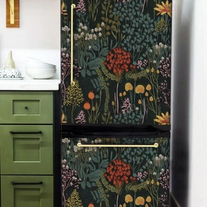 May include: A black refrigerator with a floral pattern wallpaper covering the front. The wallpaper features a variety of flowers, leaves, and mushrooms in shades of red, orange, yellow, green, and purple on a dark green background.