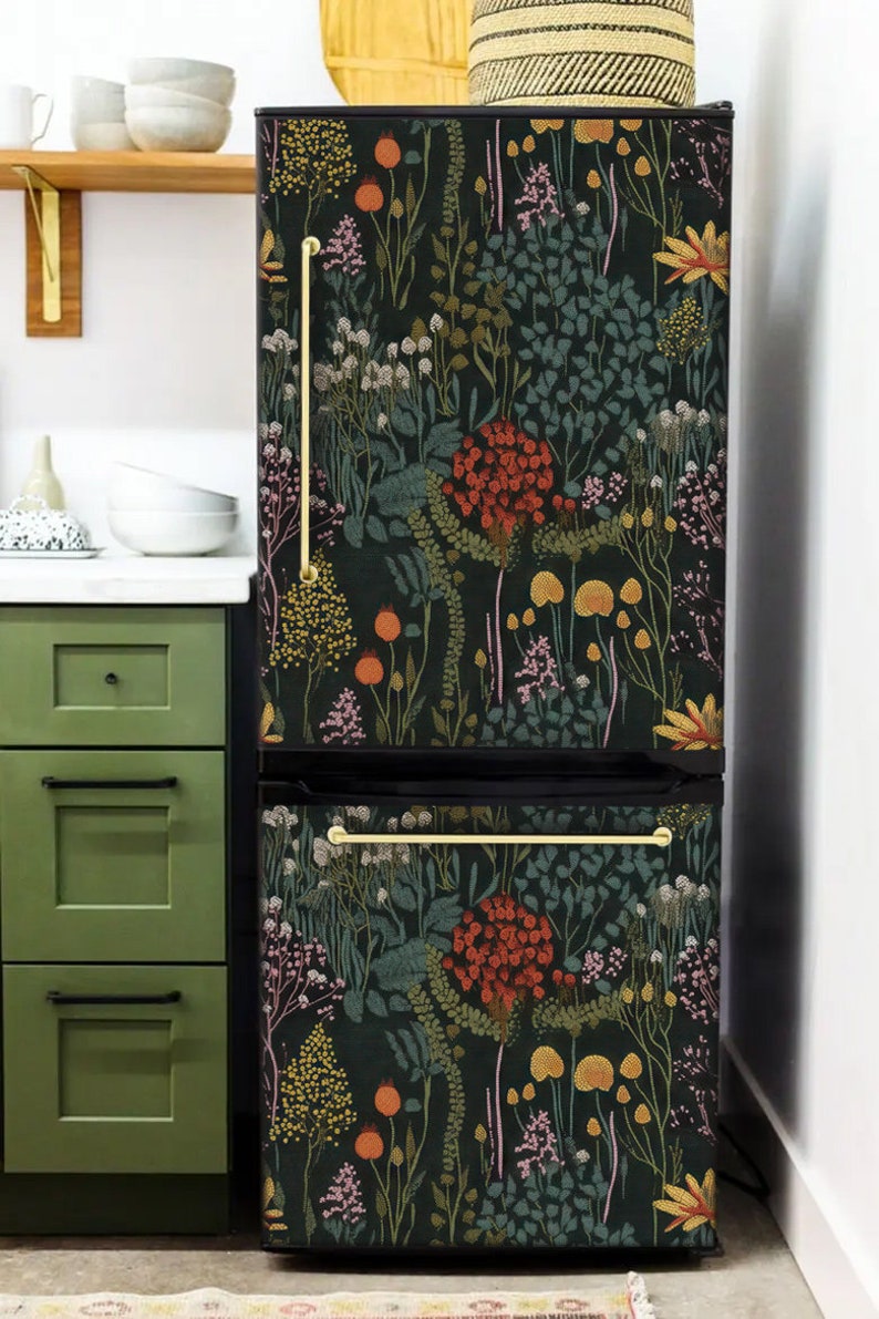 May include: A black refrigerator with a floral pattern wallpaper covering the front. The wallpaper features a variety of flowers, leaves, and mushrooms in shades of red, orange, yellow, green, and purple on a dark green background.