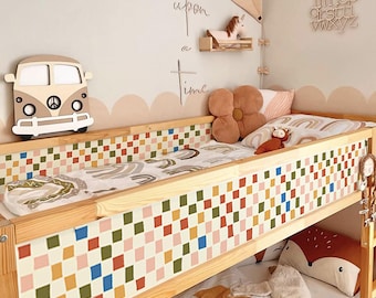 May include: A wooden bunk bed with a colorful checkered pattern on the side rails. The bed is decorated with pillows, a fox plush, and a rainbow-themed blanket. A wooden VW bus and the words "Once upon a time" are on the wall.