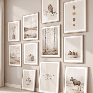 Könnte beinhalten: Eine Galeriewand mit zehn gerahmten Drucken in hellen Holzrahmen, die neutrale Illustrationen von einer Eule, Blättern, einer Landschaft, einem Wald, Birnen, einem Kürbis, Pilzen, einem Elch und einem Druck mit dem Text AUTUMN CALM zeigen.