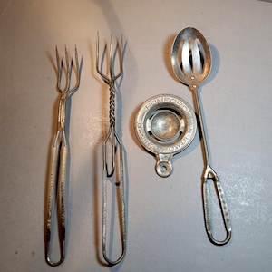 May include: Four silver kitchen utensils, including two forks, a slotted spoon, and a round egg separator with the text "Rumford Baking Powder".