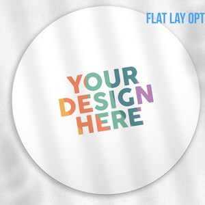 May include: White round sticker with the text "YOUR DESIGN HERE" in colourful letters. The text is arranged in a diagonal pattern with the word "YOUR" at the top and the word "HERE" at the bottom.