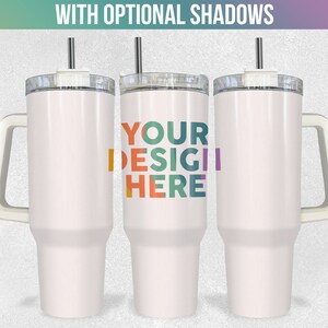 May include: Three white stainless steel travel mugs with handles and lids. The middle mug has the text "YOUR DESIGN HERE" in colourful letters.