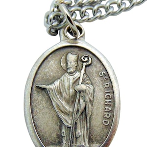 May include: Silver oval pendant necklace with a depiction of Saint Richard. The pendant features a detailed image of the saint holding a staff and wearing a mitre. The inscription "St. Richard" is engraved on the pendant.