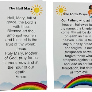 May include: Two white cards with colorful rainbows at the bottom. The Hail Mary prayer is printed on the left card. The Lord's Prayer is printed on the right card.