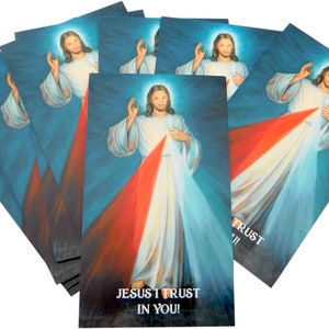 May include: A stack of religious cards featuring an illustration of Jesus with rays of red and white light emanating from his chest. The text "JESUS I TRUST IN YOU!" is printed at the bottom of the cards.