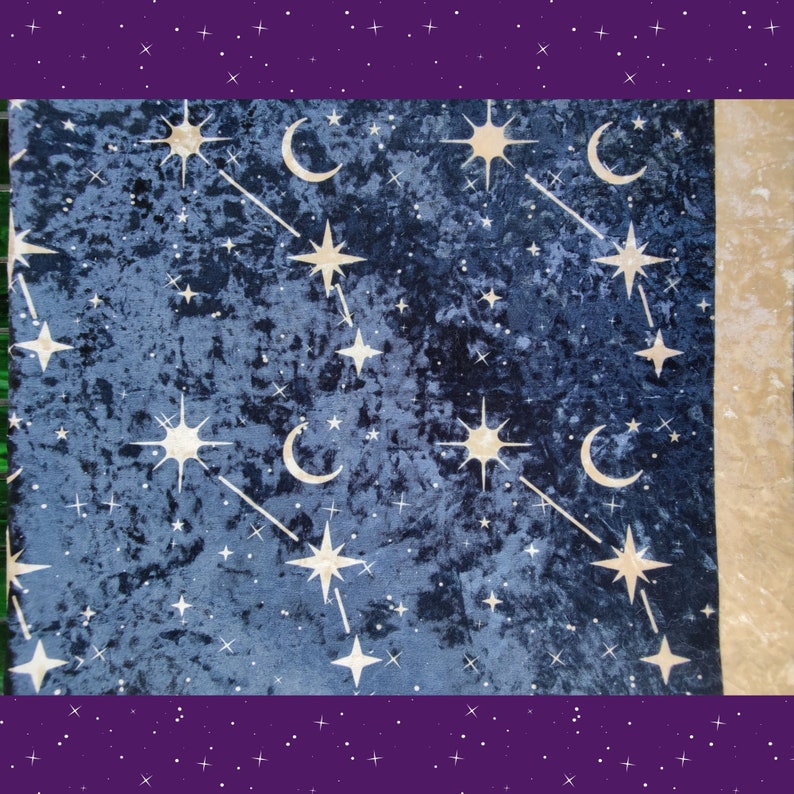 May include: A dark blue velvet fabric with a celestial pattern. The design features gold stars, crescent moons, and connecting lines, creating a night sky theme. The fabric has a soft, textured appearance.