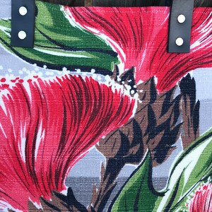 May include: A gray tote bag with red and green floral print. The bag has black leather straps with silver metal rivets.