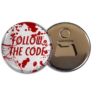 Può includere: Un apribottiglie rotondo con retro in metallo argentato e fronte bianco. Il fronte presenta schizzi rossi e le parole "FOLLOW THE CODE" in rosso. L'apribottiglie è progettato per aprire bottiglie.