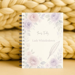 May include: A notebook with a spiral binding, adorned with a floral design of lavender and pink roses. The cover displays the text "Yours Truly, Lady Whistledown" and a feather illustration. The background is a soft, neutral colour.