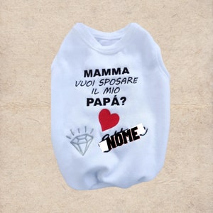 May include: White dog shirt with the text "Mamma vuoi sposare il mio Papà?" and a red heart. A diamond with sparkles is below the heart. The text "NOME" is written in black over a white rectangle.