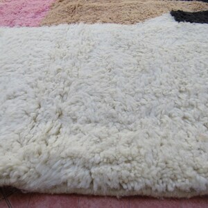 May include: Close-up of a white, fluffy rug with a soft, textured surface. The rug has a subtle, uneven pattern.