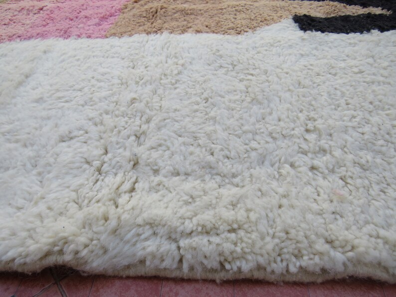 May include: Close-up of a white, fluffy rug with a soft, textured surface. The rug has a subtle, uneven pattern.