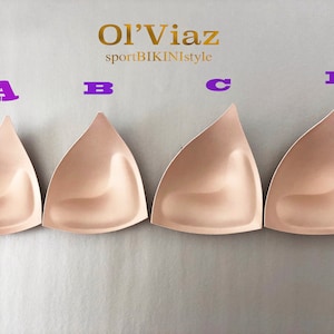 May include: Four beige foam bra cups labeled A, B, C, and D. The cups are shaped like a triangle with a rounded bottom.