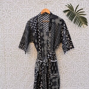 May include: Black and white patterned cotton robe with a tie belt. The robe has a patchwork design with various geometric and floral patterns.