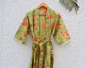 Peut inclure: Une robe de chambre florale verte avec des fleurs orange et des bordures blanches. La robe a une ceinture et une poche sur le côté gauche. La robe est suspendue à un cintre sur un fond blanc à motif floral.