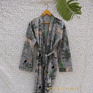 Puede incluir: Una bata de algodón gris con estampado de jungla con tucanes, leopardos y palmeras. La bata tiene un cinturón de atar y mangas largas.
