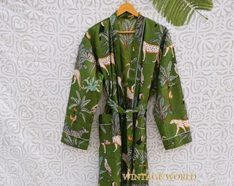 Peut inclure: Une robe en coton vert avec une bordure blanche et un imprimé jungle représentant des zèbres, des léopards, des toucans et des palmiers. La robe a une ceinture à nouer et est suspendue à un cintre en bois. "Vintage World" est imprimé dans le coin inférieur droit de la robe.