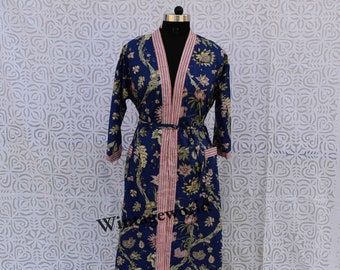 Peut inclure: Une longue robe en coton bleu avec un imprimé floral et des bordures rayées rose et blanches. La robe a une ceinture à nouer et des manches longues.